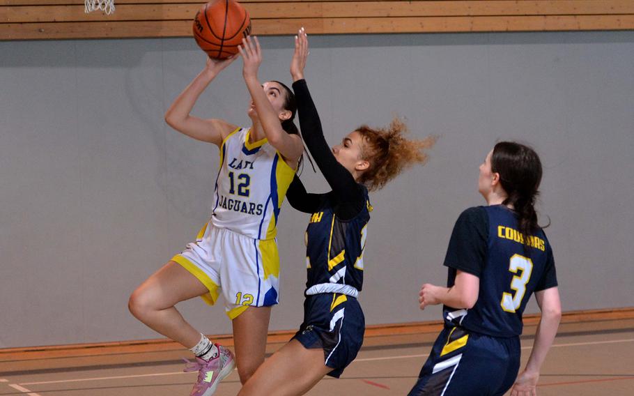 Sigonella’s  Fabiola Mercado-Rodriguez gets past Ansbach’s Laila McIntyre as teammate Trinity Batin watches the action in a Division III game at the DODEA-Europe basketball championships in Baumholder, Germany, Feb. 16, 2023. Sigonella beat the Cougars 41-18.