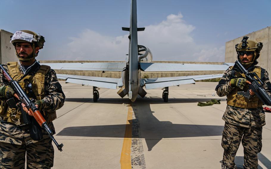 Taliban fighters stand guard behind an airplane left by U.S. forces at Hamid Karzai International Airport in Kabul, Afghanistan, Tuesday, August 31, 2021.