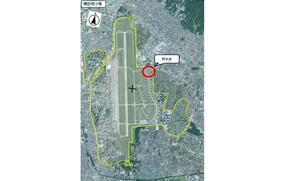 An aerial view map of Yokota Air Base with text in Japanese next to a red circle. 
