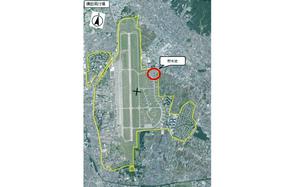 An aerial view map of Yokota Air Base with text in Japanese next to a red circle. 