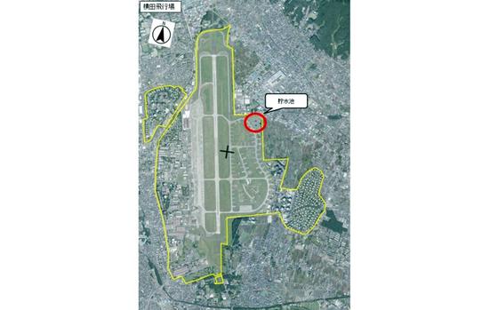 An aerial view map of Yokota Air Base with text in Japanese next to a red circle. 