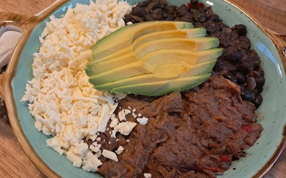 Pabellon criollo is the national dish of Venezuela. It normally has fried plantains to match the yellow in the Venezuelan flag. The order pictured here has avocado, cheese, black beans and shredded beef with minced red peppers, but no plantains at the customer's request.