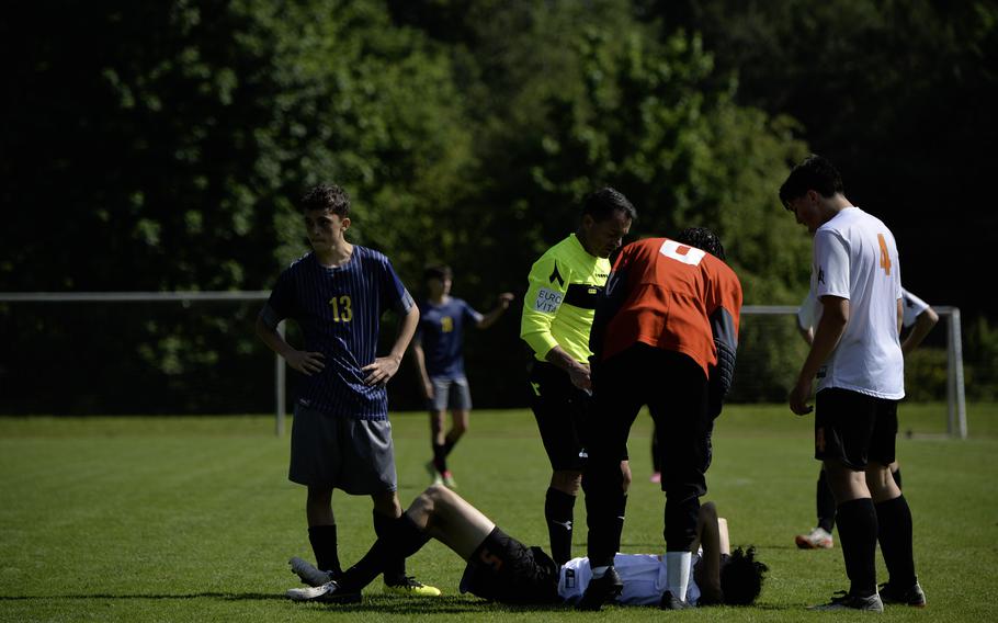 Ansbach’s Daymien Abitua, left,  and Spangdahlem’s Logan Simmers, right, look on as Mason Tieyah lies on the ground after a foul during the 2024 DODEA European Soccer Division III Championships in Landstuhl, Germany, on May 20, 2024.