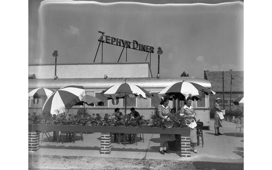 Roedelheim, Germany, June 17, 1950: Diner patrons eat under cheerful parasols on the outside terrace of the Zephyr Diner. The diner - which opened in 1949 as part of the European Exchange System - is located on the autobahn north of Frankfurt, on the Westerbachstrasse, Roedelheim. It was the first diner in the European Command area. It no longer exists,, but it is unknown when it closed. 

Looking for Stars and Stripes’ historic coverage? Subscribe to Stars and Stripes’ historic newspaper archive! We have digitized our 1948-1999 European and Pacific editions, as well as several of our WWII editions and made them available online through https://starsandstripes.newspaperarchive.com/

META TAGS: Europe; Germany; European Exchange Sytem; diner; dining; food service; leisure; military life; restaurant; fast food