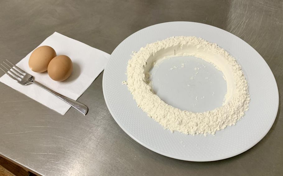 eggs on a napkin with a fork on the left, a circle of flour on the right