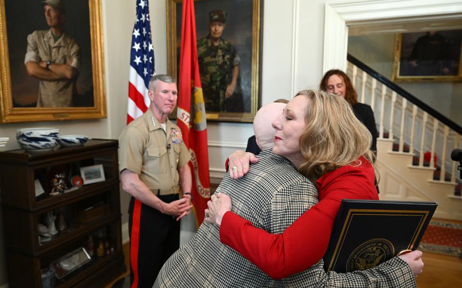 Joyce LaLonde embraces Patrisha Smith, in red, the wife of Gen. Eric M. Smith, left, as Gen. Smith recognizes Joyce and others during the ceremony Thursday. 