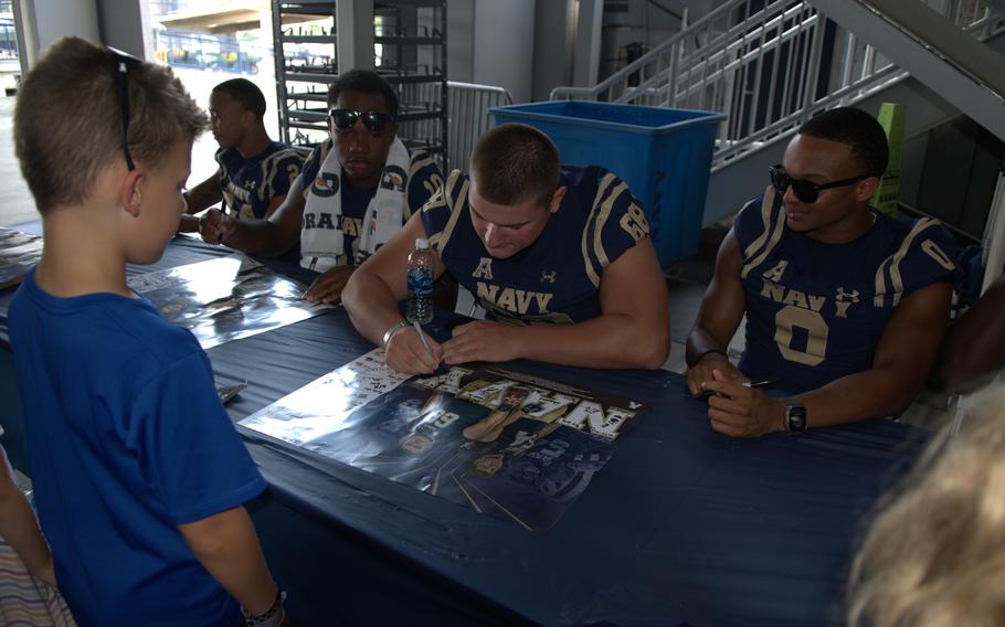 Senior center Lirion Murtezi signs a poster at Navy Football FanFest on July 29, 2023, on the concourse of Navy-Marine Corps Memorial Stadium in Annapolis, Md.