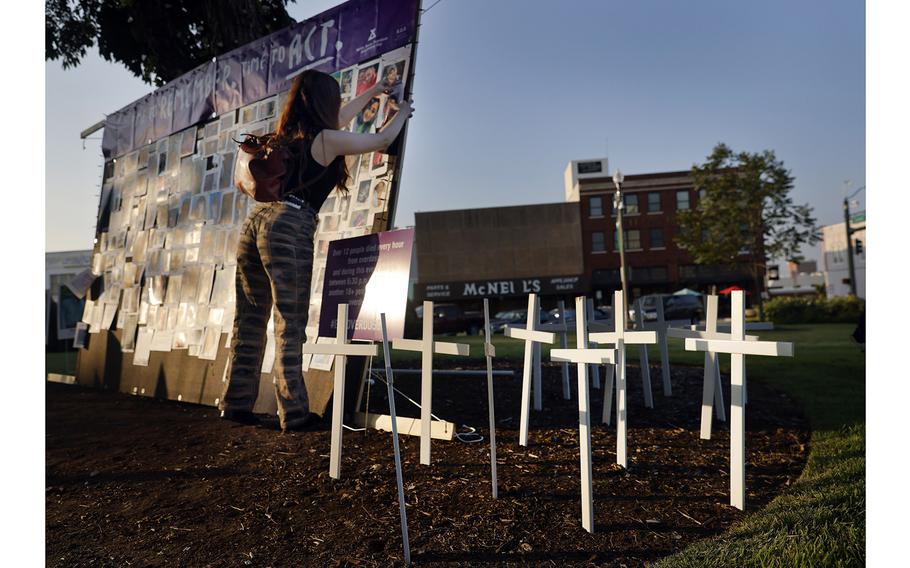 Ashleigh Calvert reattaches a fallen photo to a memorial wall erected at the North Texas Overdose Awareness Day event outside Denton County Courthouse-on-the-Square Museum on Aug. 31, 2023.