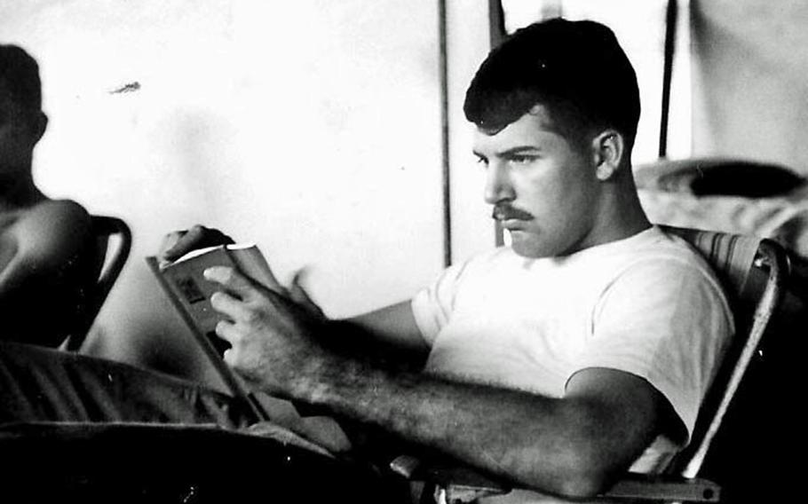 A man in a black and white photo reads a book.