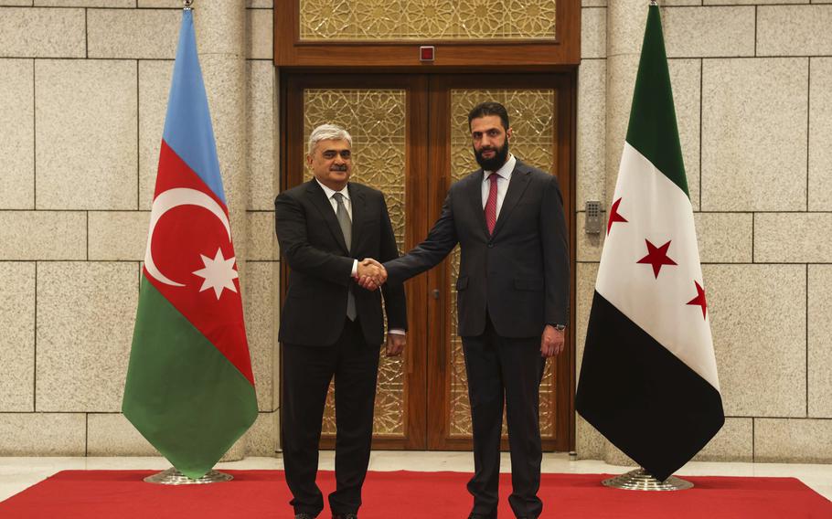 Syrian President Ahmad al-Sharaa, right, shakes hands with Azerbaijani Deputy Prime Minister Samir Sharifov