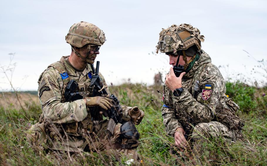 A U.S. Army soldier coordinates with a paratrooper from the Lithuanian-Polish-Ukrainian Brigade after conducting a joint airborne operation near Yavoriv, Ukraine in September 2021. A recent Rand Corp. study suggests  the Army should emphasize lighter units over tanks as a deterrent against Russia. 