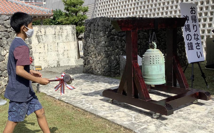 A sign, “Welcome back to Okinawa,” stands next to a bronze temple bell at the entrance to the Okinawa Prefectural Museum & Art Museum in Naha, Tuesday, Nov. 2, 2021.
