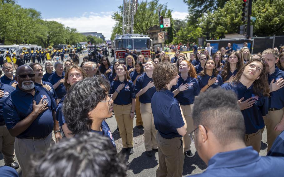A chorus, with hands on the hearts, sings the national anthem.
