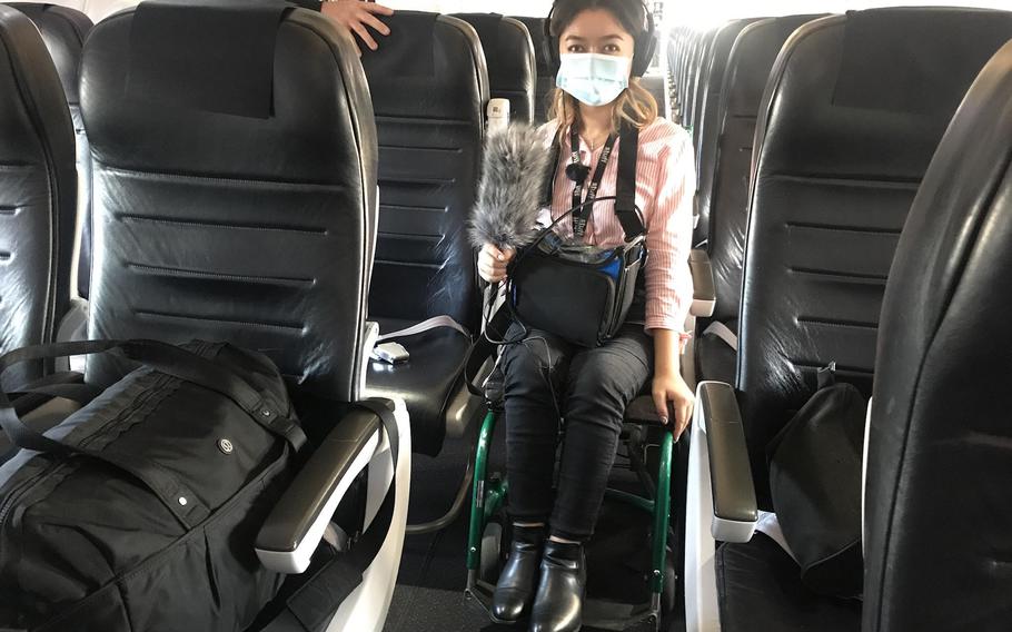 As airplane aisles are too narrow for her wheelchair, Olivia Shivas borrows one to board the plane. 