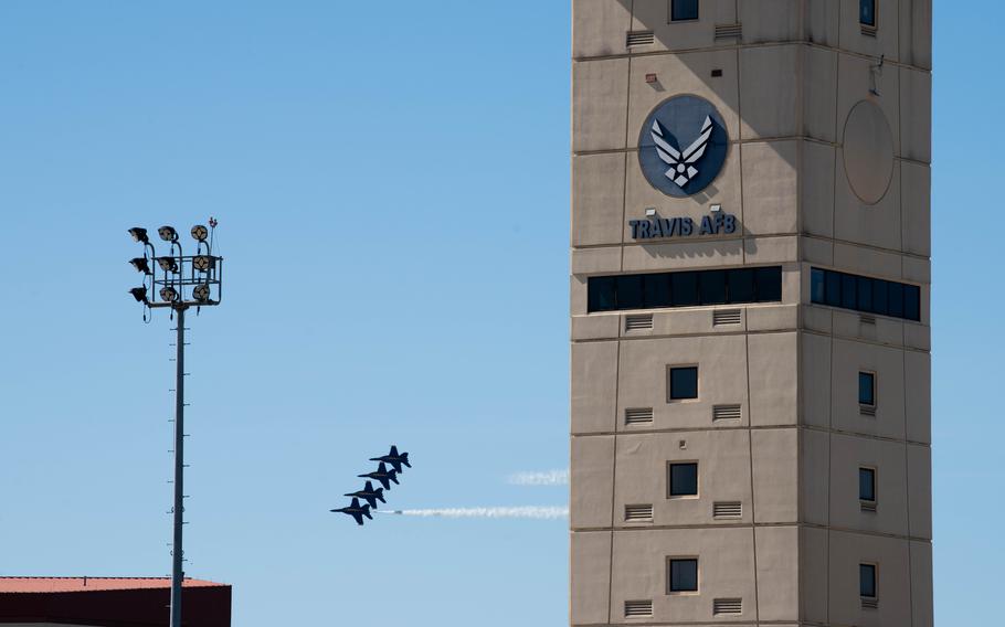 A control tower reading “Travis AFB” is seen in the foreground with a group of fighter jets soaring in the background against a blue sky.