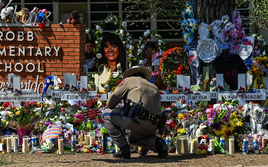 A police officer clears the makeshift memorial at Robb Elementary School in Uvalde, Texas, on May 29, 2022. 