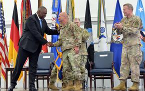 Defense Secretary Lloyd Austin congratulates Gen. Christopher Cavoli, the new head of U.S. European Command, as the Chairman of the Joint Chiefs of Staff Gen. Mark Milley, center, and the outgoing commander Gen. Tod Wolters applaud at a ceremony in Stuttgart, Germany, July 1, 2022. 