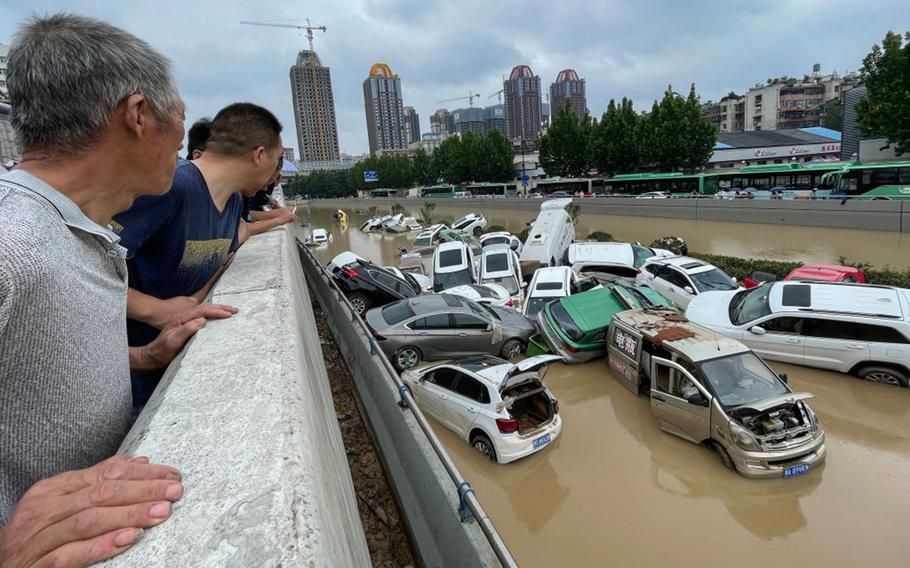 People look out at cars sitting in floodwaters after heavy rains hit the city of Zhengzhou in China's central Henan province on July 21, 2021. Soon, weather scientists will have an even stronger pair of eyes in the sky once a new advanced weather satellite launches this March.