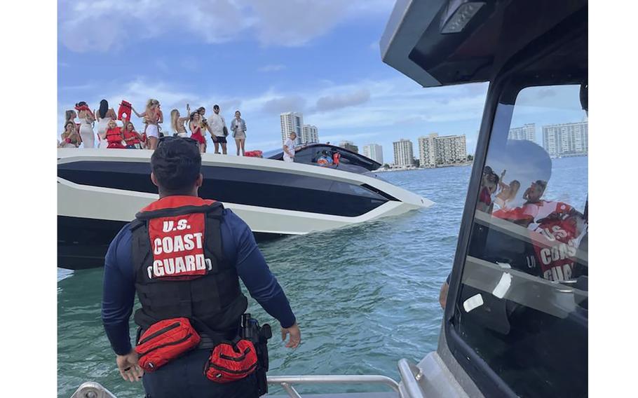 A U.S. Coast Guard member rescuing people on a sinking yacht