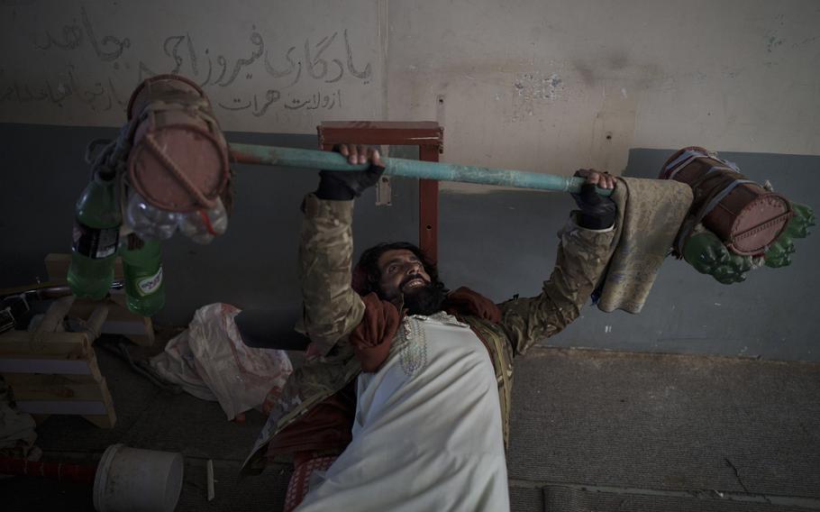 A Taliban fighter lifts makeshift weights left behind by former prisoners at an empty area of the Pul-e-Charkhi prison in Kabul, Afghanistan, Monday, Sept. 13, 2021.