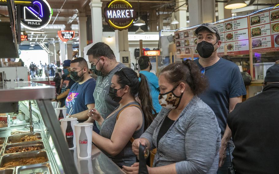 Customers wait in line to order food inside the Grand Central Market on Broadway in downtown Los Angeles. California’s new mask mandate comes amid growing concerns that a winter surge in COVID-19 cases could once again strain hospitals.