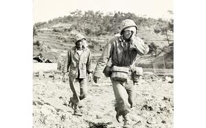 Two injured military members walk to medical treatment.