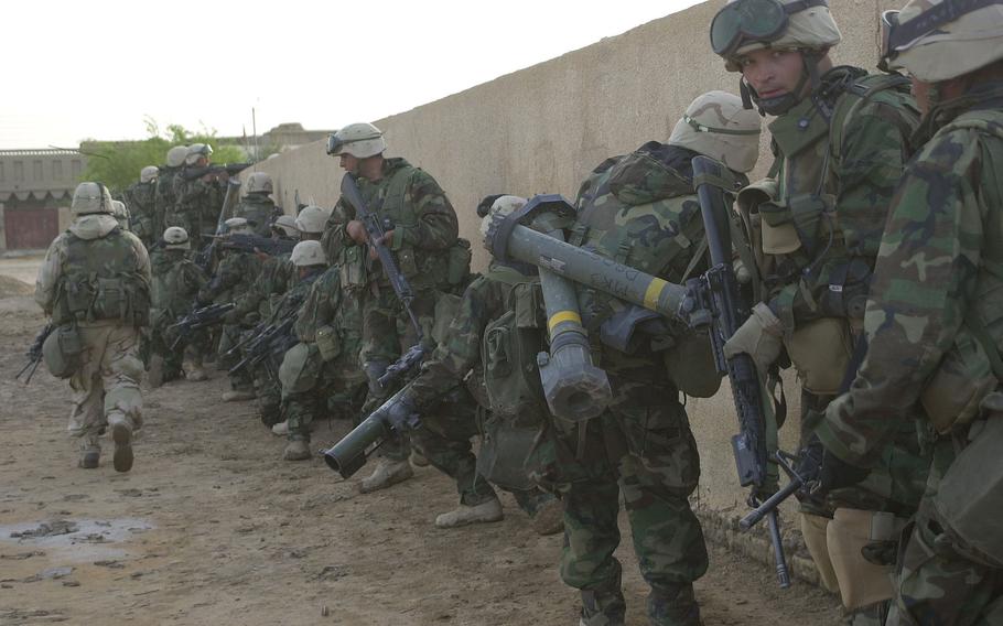 Marines from Company G, 2nd Battalion, 23rd Marines, prepare to jump a wall into a schoolhouse duing a raid at Al Fahr, Iraq. The raid netted weapons, intelligence and several Baath Party officials captured.      