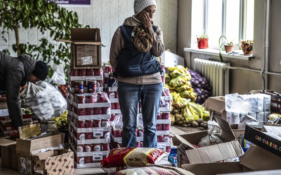 Vorzel resident Larissa Shudeva, carrying her dog, pauses in her volunteer work sorting food and clothing donations at a school. 