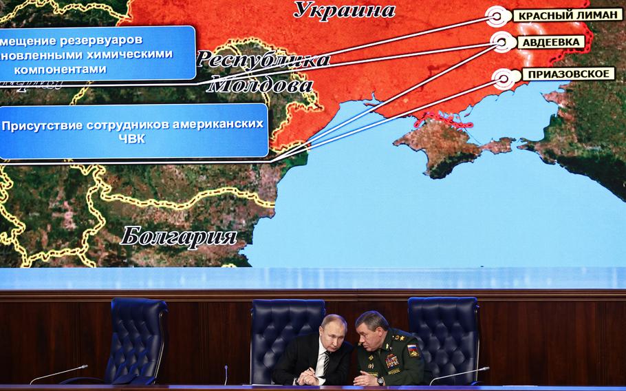 Russian President Vladimir Putin, left, and Russian General Staff Valery Gerasimov talk  at the National Defense Control Center in Moscow, Russia, on Dec. 21, 2021, with a Russian military map showing the alleged deployment of U.S. private military contractors in eastern Ukraine in the background.
