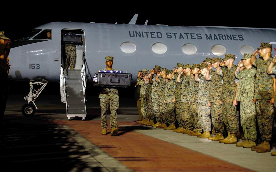 Marines saluting as remains are transported.