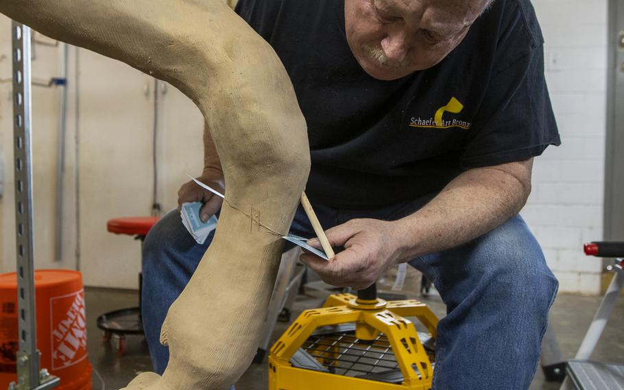 Tommy Ladd, owner of Schaefer Art Bronze Casting, uses playing cards to mark the areas where the statue will be cut and molded. The statue is taken apart before being cast in bronze at the foundry. 