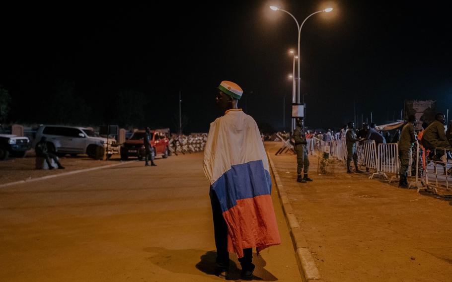 A man wears a Russian flag at the Rond-Point de l’Escadrille while attending a concert.