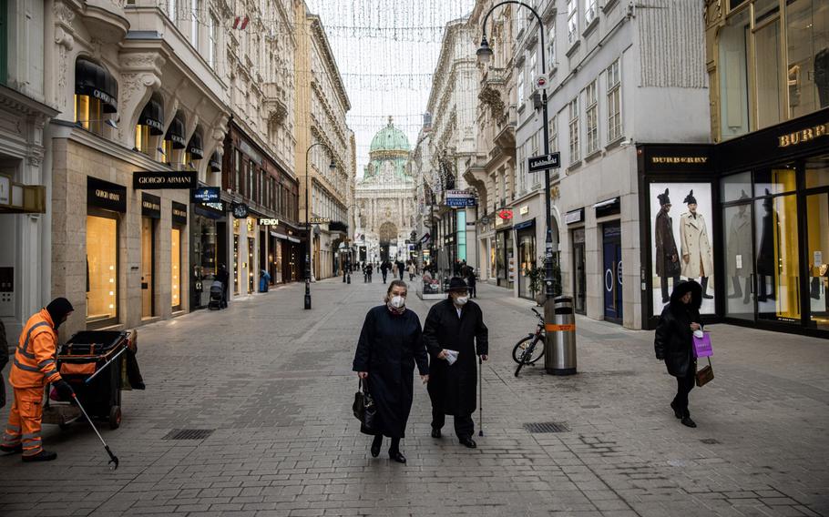 Masked pedestrians walk along a quiet retail street in Vienna on Nov. 22, 2021.