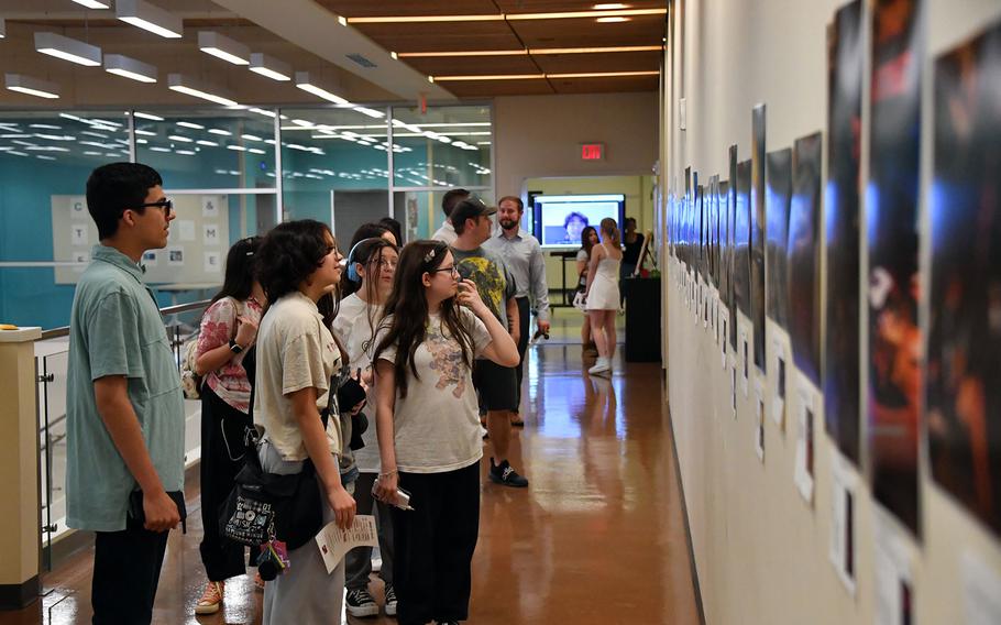 Students and visitors look at photographs on display.
