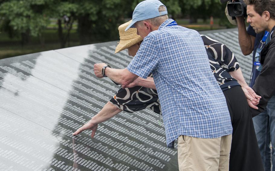 Vietnam veteran Terry Ogle takes a picture as his wife Anne McEnerny-Ogle reaches out to touch the name of her uncle, Charles D. McEnerny, engraved on the new Wall of Remembrance at the Korean War Memorial in Washington, D.C., on Tuesday, July 26, 2022.