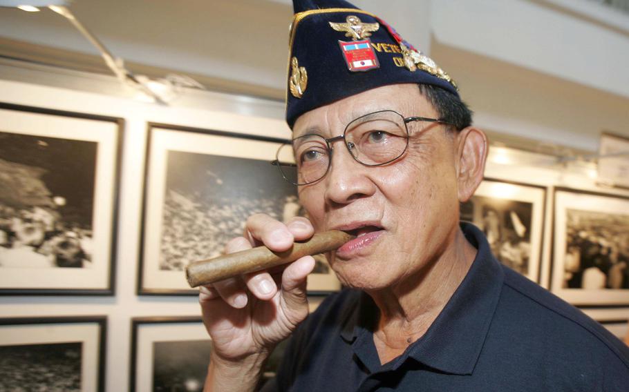 Former Philippine President Fidel Ramos bites his cigar as he looks on photographs during an exhibit on the 20th anniversary of "People Power" in suburban Makati, south of Manila, Philippines, on Feb. 22, 2006.