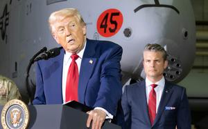 President Donald Trump speaks into a podium microphone, while Defense Secretary Pete Hegseth listens from behind him.