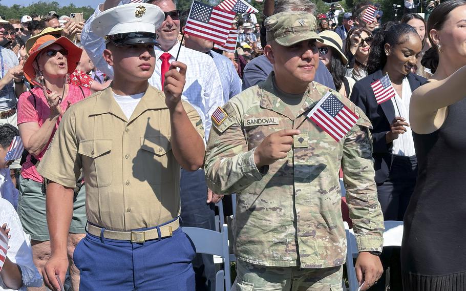 A Marine and Army service members waiving the flag of the United States after celebrating becoming US citizens.