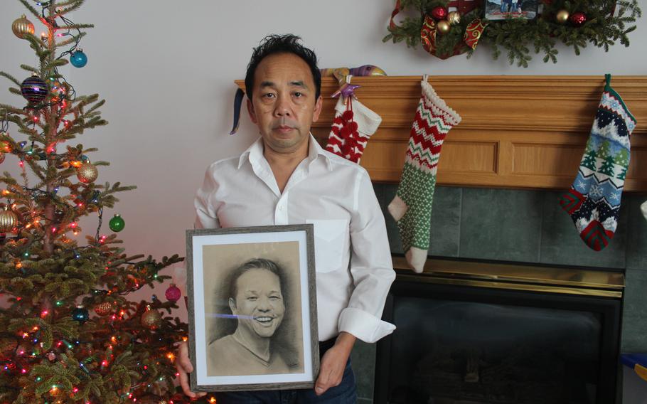 Eh Xiong holds a portrait of his late brother in his home in Woodbury, Minn., in December.