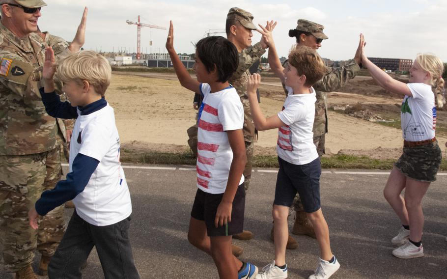 From left to right, Maj. Mark Fitzgerald, Capt. Bau Phan and Lt. Col. Kimberly Baird of the Texas National Guard high-five Dutch children as they arrive to take part in a ceremony in Nijmegen, Netherlands, on Sept. 20, 2021, to remember the crossing of the Waal River by U.S. soldiers 77 years earlier.