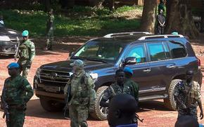 Armed security personnel stand around a black van.