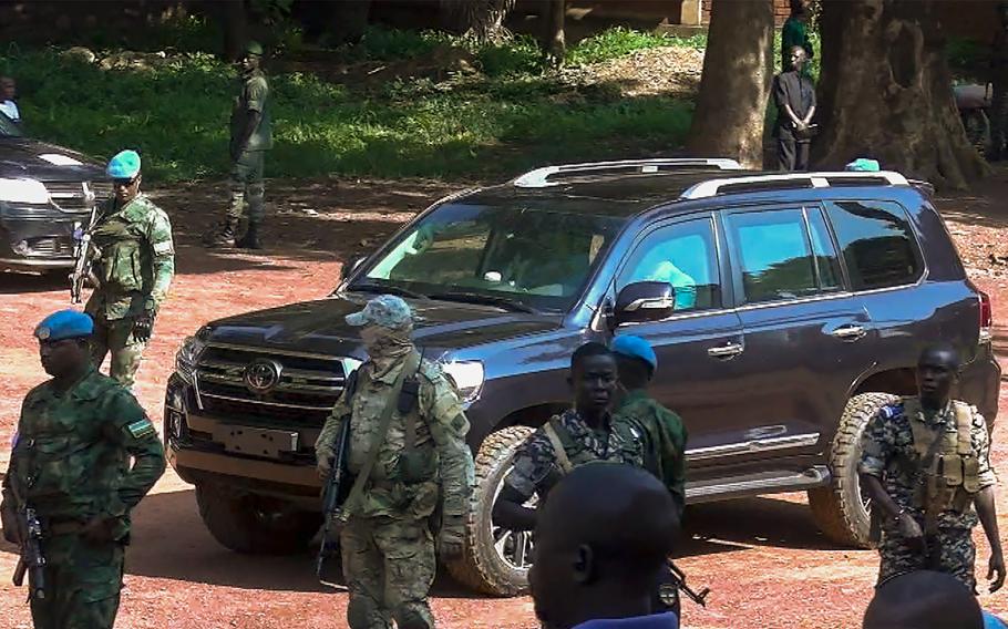 Armed security personnel stand around a black van.