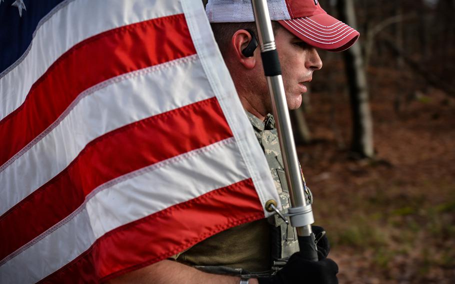 Air Force Master Sgt. Trevor Derr, flight chief assigned to the 721st Aircraft Maintenance Squadron, runs with an American flag at Ramstein Air Base, Germany, Dec. 7, 2021. Derr carries the flag and wears body armor during his runs to honor the memory of a fellow airman he lost to suicide and raise awareness of post-traumatic stress disorder.