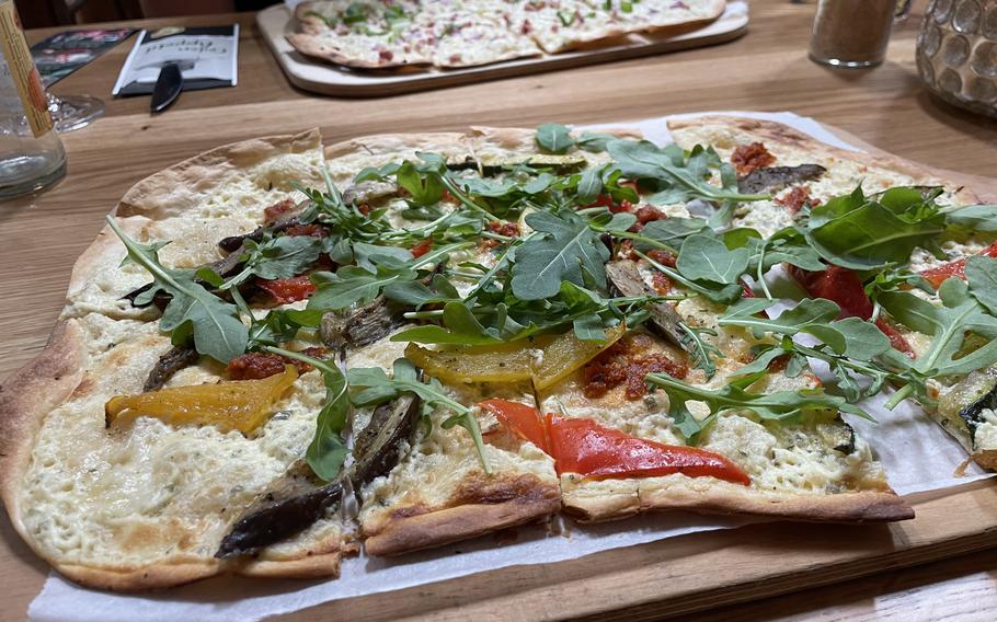 A flammkuchen topped with leafy greens.
