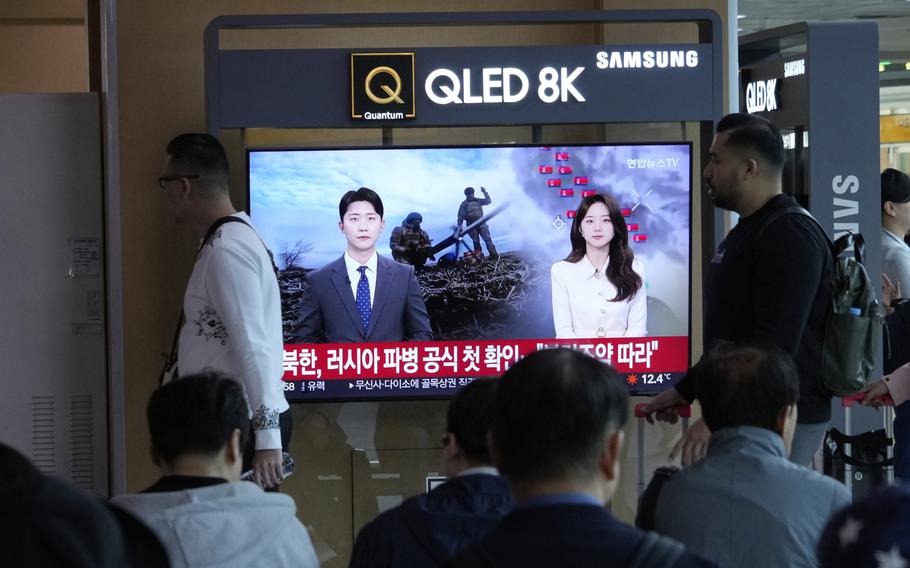 People pass by a TV screen reporting that North Korea confirmed its troops deployed to Russia during a news program.