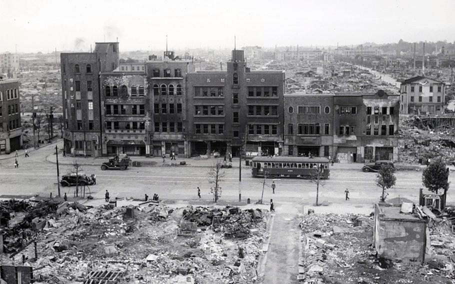 A black and white photograph shows the destruction of buildings in Tokyo due to firebombing.