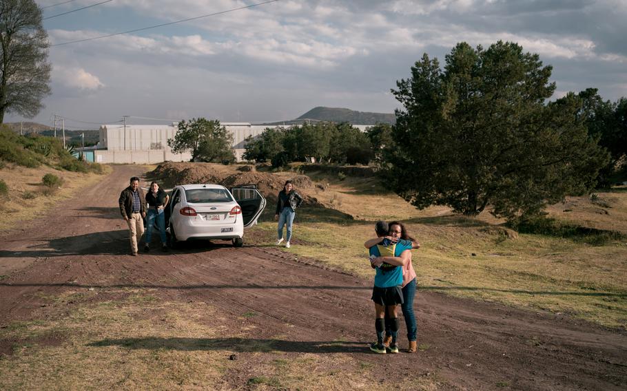 German Silva hugs a niece who came to see him running while the rest of her family wait by their car on a dirt road. Silva has been constantly accompanied by family members and people from the athlete community through his journey. 