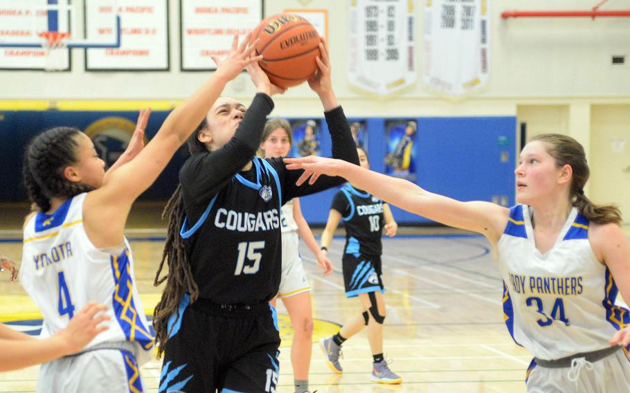 Osan's Zephaniah Martin shoots between Yokota defenders Coco Jones and Kayla Bogdan. The Panthers edged the Cougars 44-40.