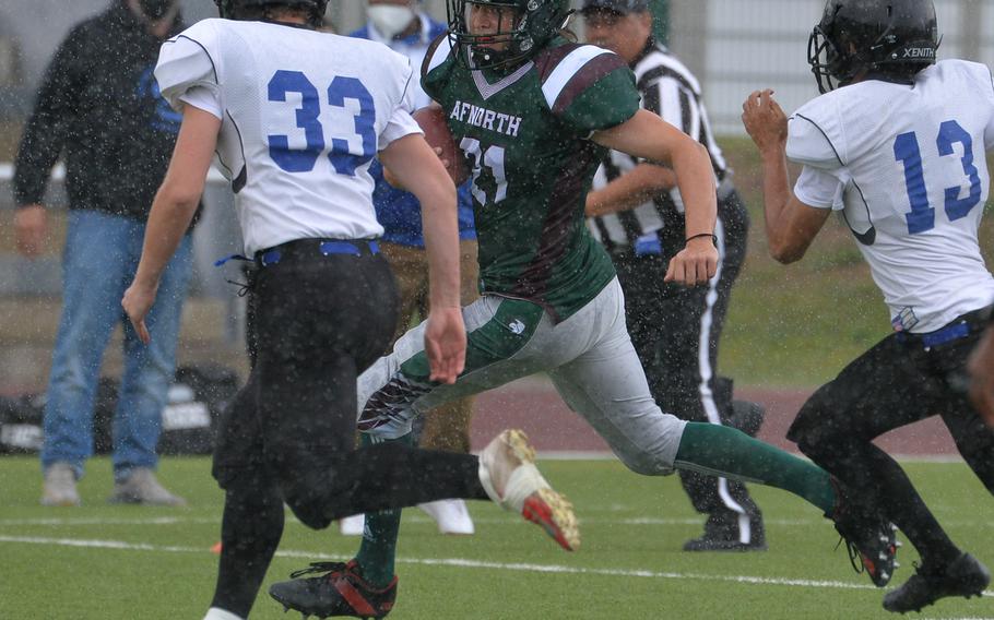 After pulling in a pass, AFNORTH’s Alexander Roberts heads upfield against the Hohenfels defense of Hunter Naples, left, and Robert Ellertson. AFNORTH won the Division III game played at Kaiserslautern High School, Saturday, Sept. 11, 2021, 76-28.