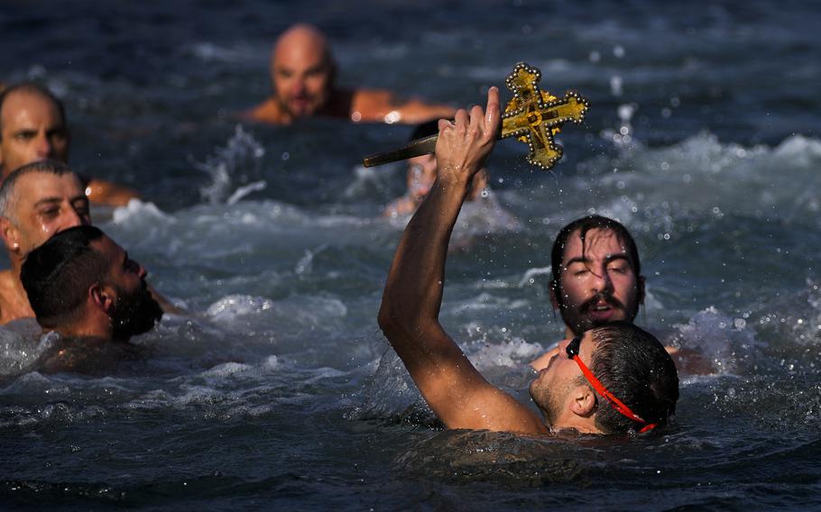 A Greek Orthodox faithful holds up a wooden crucifix after retrieving it in the Golden Horn during the Epiphany ceremony in Istanbul, Turkey, Thursday, Jan. 6, 2022. 
